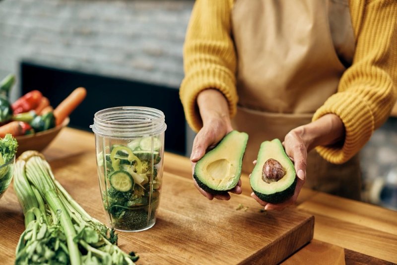 Person measuring avocado portion with kitchen scale for calorie tracking